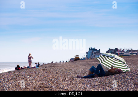 Rentner sitzen unter Sonnenschirm am Strand Stockfoto