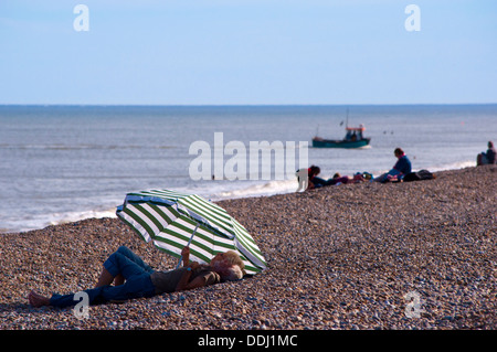 Rentner sitzen unter Sonnenschirm am Strand Stockfoto