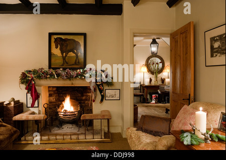 Kamin mit Club Kotflügel im gemütlichen Wohnzimmer mit Howard Stil Sessel und Blick durch Hall Stockfoto