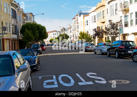 Wohnstraße in San Francisco mit parkenden Autos und malerischen Häuserzeilen in schrägen Licht gesehen. Stockfoto