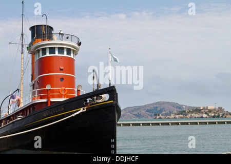 Hercules, ein Hochsee-Schlepper ist angedockt an der Hyde Street Pier in San Francisco Bay mit Blick auf Alcatraz im Hintergrund Stockfoto