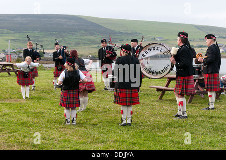 Die Rendall Pipe Band erklingt in Finstown, Orkney, anlässlich eines Besuchs von der lokalen Chip-van. Stockfoto