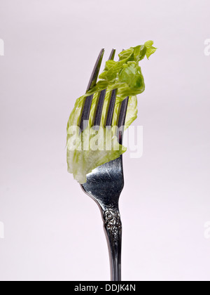 Ein Stück Salat ist auf eine aufrechte Gabel geschlagen. Stockfoto