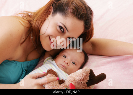 Glückliche Mama und Baby Boy lächelnd im Bett halten Teddybär Stockfoto