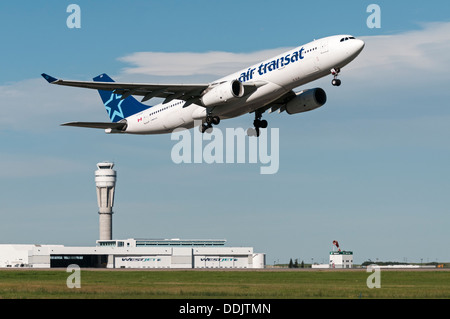 Ein Air Transat Airbus A330 Widebody Jetliner startet vom Calgary International Airport, Flughafen-Gebäude im Hintergrund. Stockfoto