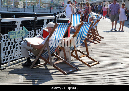 Leute sitzen in Liegestühlen auf der Pier, Brighton, East Sussex, England, UK Stockfoto