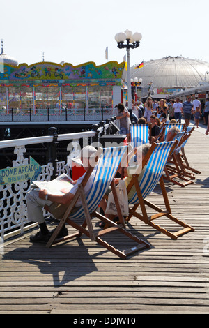 Leute sitzen in Liegestühlen auf Brighton Pier East Sussex England UK Stockfoto