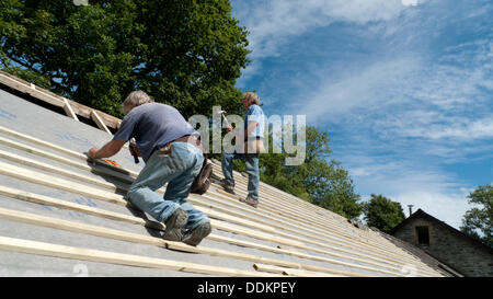 Bauunternehmen Dachdecker Brian White und Jim Hill, ein neues Dach auf einer ländlichen walisischen Steinscheune Haus Zuhause bei herrlichen Sonnenschein Wetter Llanwrda, Carmarthenshire Dyfed Wales UK KATHY DEWITT Stockfoto