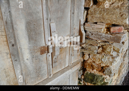 Alte hölzerne Scheunentor Riegel und inneren Steinmauer. Stockfoto