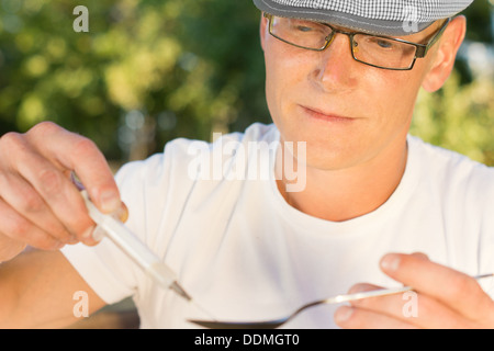 Close-up horizontale Porträt des Heroin Konsumenten eine Spritze mit löslichen Medikamentendosis zu füllen Stockfoto