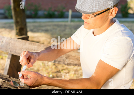 Männliche Heroin Täter eine injizierbare Medikamentendosis zu nehmen, im Freien wird vorbereitet Stockfoto