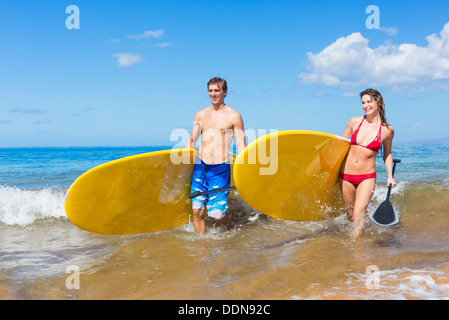 Attraktives Paar mit Stand Up Paddle Boards, SUP, am Strand von Hawaii Stockfoto