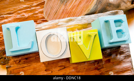 Das Wort Liebe in großen Druckbuchstaben auf einem rustikalen hölzernen Hintergrund geschrieben Stockfoto