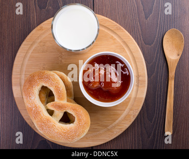 Weiche Brezeln, Marillenmarmelade und Glas Milch Stockfoto