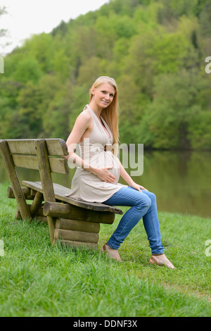 Junge schwangere Frau sitzen auf einer Bank Stockfoto