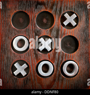Spiel von Tic Tac Toe oder Nullen und Kreuze auf einem Holzbrett mit Metallteilen Stockfoto