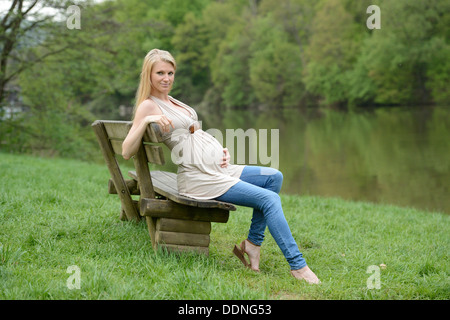 Junge schwangere Frau sitzen auf einer Bank Stockfoto