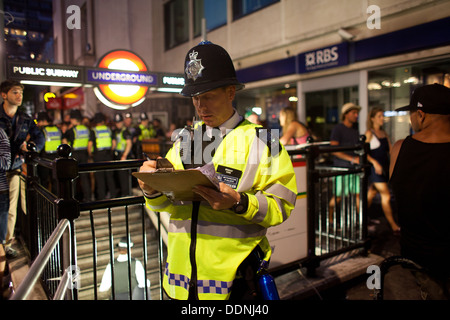 Die u-Bahnstation Notting Hill ist überfüllt und Polizei halten strenge Kontrolle über dem Eingang. Ein Polizist verfolgt. Stockfoto