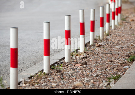 Gestreifte rote und weiße Signal Pole auf Asphalt am Straßenrand stehen Stockfoto
