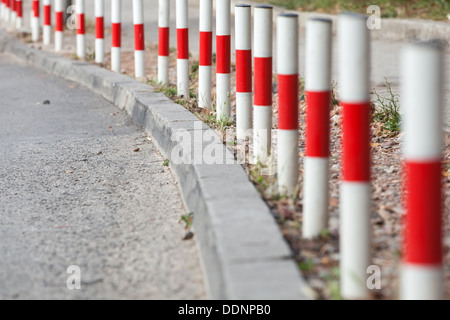 Gestreifte rote und weiße Signal Polen stehen am Rand des Asphalt-Straße Stockfoto