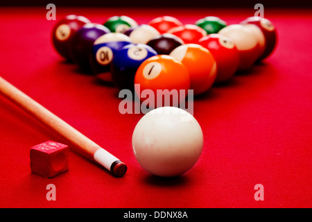 Pool-Billard-Spiel. Spielball, Cue, Farbkugeln im Dreieck, Kreide. Rotes Tuch-Tabelle Stockfoto