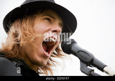 Junger Mann in Hut singen mit Mikrofon Stockfoto