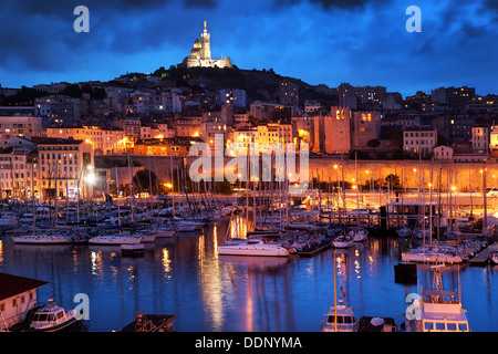 Marseille, alter Hafen / Vieux Port, Frankreich bei Nacht mit Blick auf die Basilika Notre Dame de la Garde auf dem Hügel bei Nacht Stockfoto