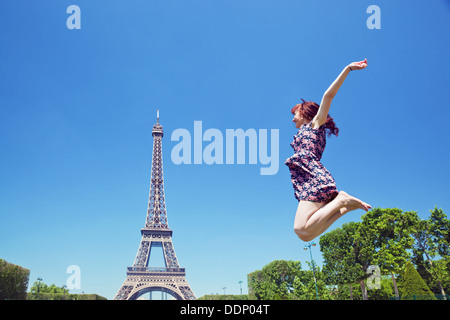 Young happy woman jumping for joy against Eiffel Tower in Paris, France Stockfoto