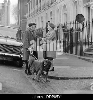 Ein älterer Mann plaudert, eine ältere Frau auf dem Bürgersteig, London, c1946-c1959. Künstler: John Gay Stockfoto