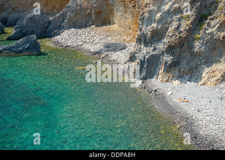 Eine Frau Sonnenbaden an einem steinigen Strand unterhalb der Punta Milazzese auf Panarea auf den Äolischen Inseln, Messina, Sizilien, Italien Stockfoto