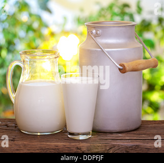 Milch in verschiedenen Gerichten auf dem alten Holztisch im Freien. Stockfoto