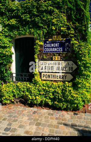 Französische Verkehrszeichen auf Efeu bedeckt Haus. Stockfoto