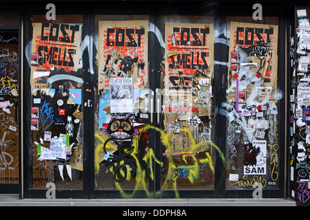Eine Wand an einem geschlossenen Restaurant in Williamsburg, Brooklyn, New York mit Graffiti, Tags, zerrissenen Postern und Aufklebern. Stockfoto