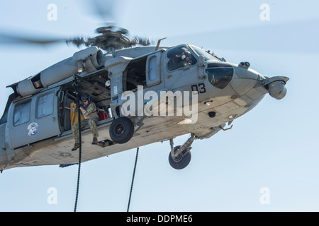 Ein Seemann, Explosive Ordnance Entsorgung Mobile Einheit (EODMU) 5 schnell-Seile von einem MH-60 s Sea Hawk auf dem Flugdeck zugewiesen Stockfoto