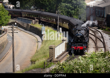 Ein Junge, einen Dampfzug Rennen, wie es aus Keighley Bahnhof Keighley und Wert Valley Railway zieht. Stockfoto