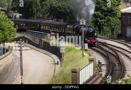 Ein Junge, einen Dampfzug Rennen, wie es aus Keighley Bahnhof Keighley und Wert Valley Railway zieht. Stockfoto