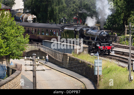 Ein Junge, einen Dampfzug Rennen, wie es aus Keighley Bahnhof Keighley und Wert Valley Railway zieht. Stockfoto