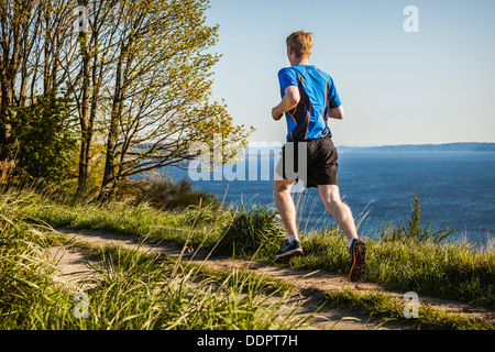 Ein junger Mann, der Treppenstufen auf einem Pfad im Discovery Park, Seattle, Washington, USA, hinunterläuft. Stockfoto