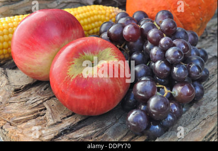 schwarze Traube mit roten Äpfeln auf hölzernen Hintergrund Stockfoto