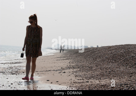 Junge Wanderer schlendern entlang eines nebeligen Kieselstrands in Aldeburgh, Suffolk, Großbritannien – eine ruhige Küstenszene, die die atmosphärische Einsamkeit der britischen Küste festhält Stockfoto