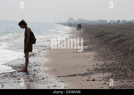 Junge Wanderer schlendern entlang eines nebeligen Kieselstrands in Aldeburgh, Suffolk, Großbritannien – eine ruhige Küstenszene, die die atmosphärische Einsamkeit der britischen Küste festhält Stockfoto