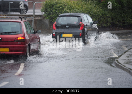 Autos fahren durch eine überschwemmte Straße, Schottland. Stockfoto