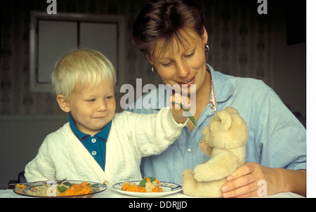 Mutter und Sohn Teddy Fütterung Sohn, seine Nahrung zu essen zu fördern Stockfoto