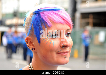 Eine junge Frau hat Haare gefärbt rot, weiß und blau mit Piercings. Stockfoto