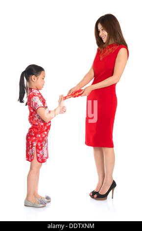 Asiatische chinesisches Kind empfangen rot Papier Paket oder monetäre von übergeordneten an Chinese New Year Festival, mit traditionellen Cheongsam isoliert auf weißem Hintergrund. Stockfoto