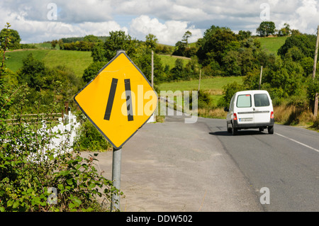 Gelbes Schild auf der Landstraße, die Warnung, dass der Weg schmal wird Stockfoto