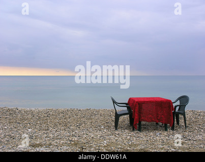 Zwei Stühle und Tisch mit knalligen roten Tischdecke am Ocean Beach, am frühen Morgen Stockfoto