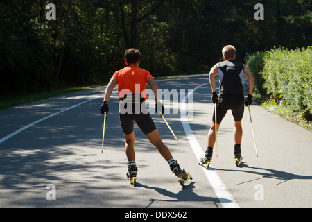 Zwei junge Mann praktizierender Rollerski im Park (als ein Sommer-Äquivalent der Langlauf). Kattowitz, Polen. Stockfoto