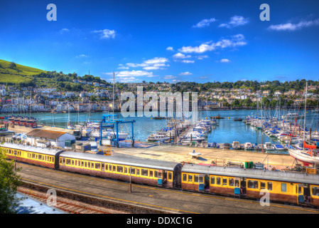 Dartmouth Bahnhof Devon England mit einem Zug mit gelben Wagen und die Stadt im Hintergrund mit blauer Himmel in HDR Stockfoto