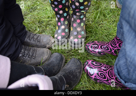 Menschen, die einander tragen Gummistiefel und Stiefel stehen in einem nassen Feld auf einem Sommer-Musikfestival in England gegenüber stehen Stockfoto